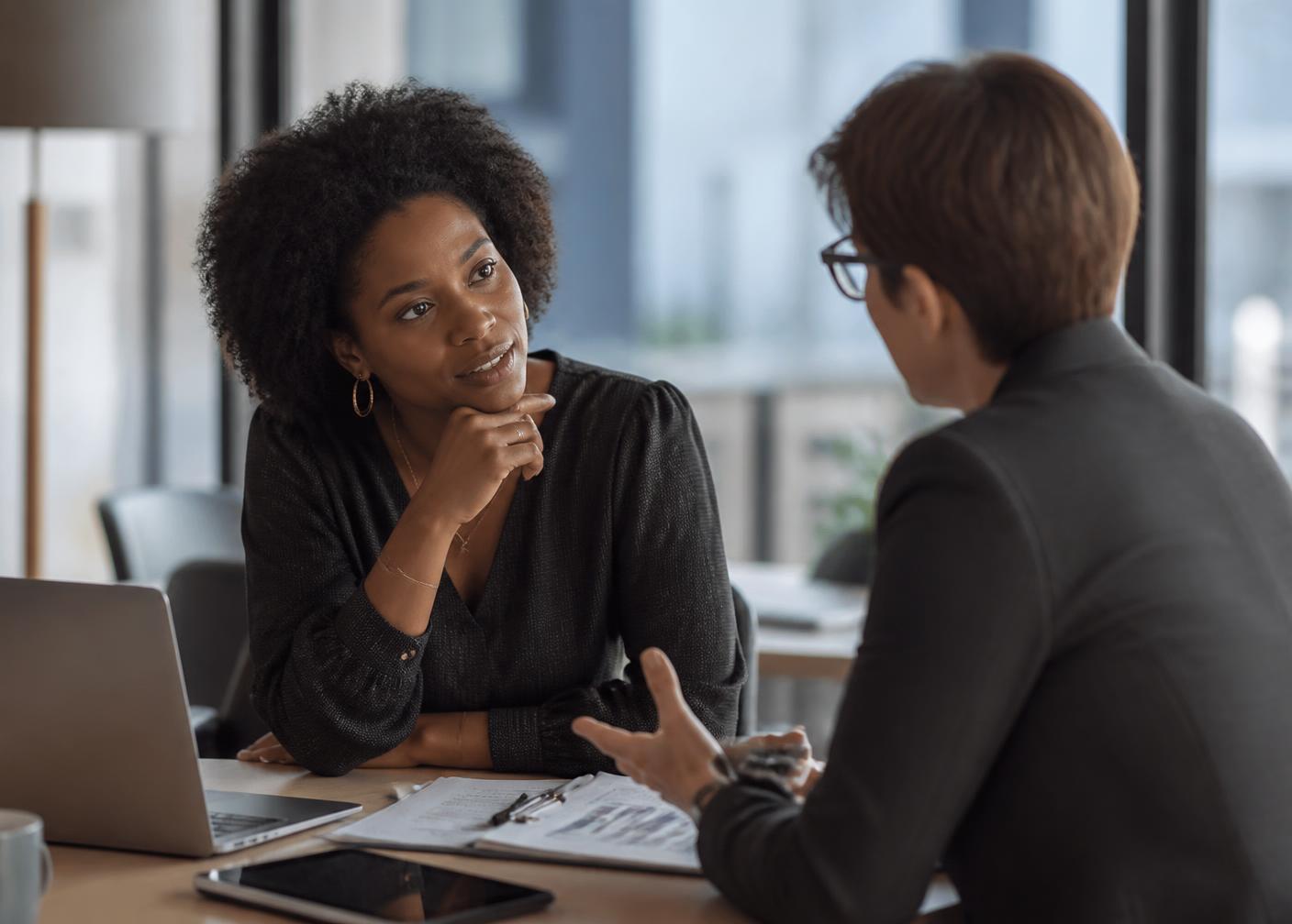 An HR consultant advising a leader across a table in a modern office